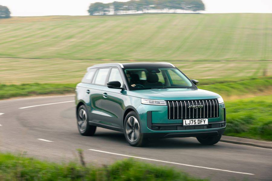 Teal colour JAECOO 5 driving down a country road with green fields