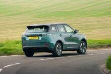 Rear shot of teal colour JAECOO 5 driving down a country road with green fields