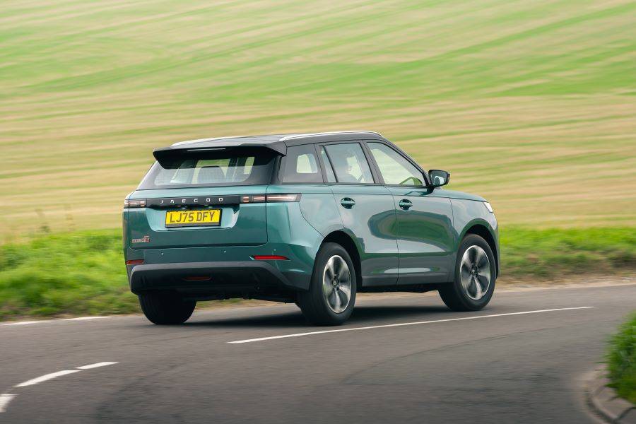 Rear shot of teal colour JAECOO 5 driving down a country road with green fields