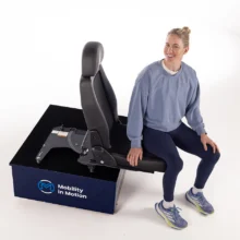 Robyn Love in a studio demonstrating a BraunAbility manual swivel seat.