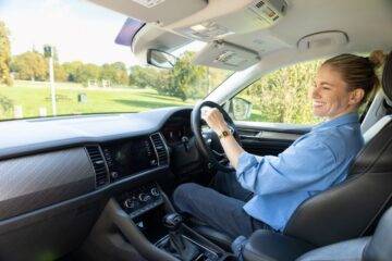 Robyn Love smiling while driving adapted car on a sunny day