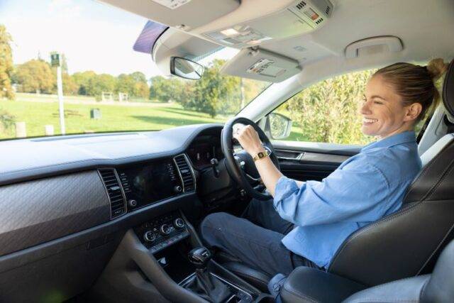 Robyn Love smiling while driving adapted car on a sunny day